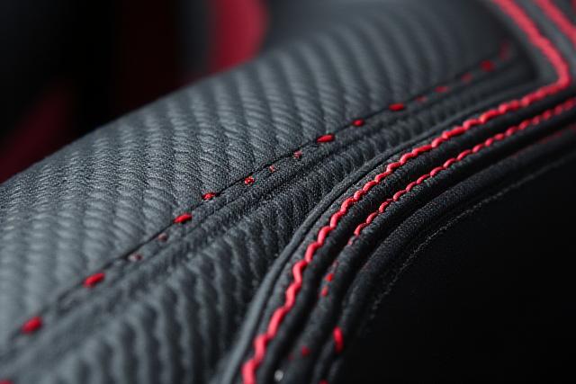 Dettaglio di interni auto sportive con inserti in fibra di carbonio lucida e cuciture rosse